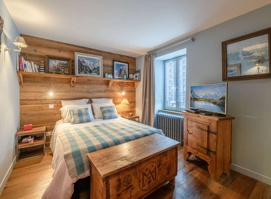 This cozy bedroom features a rustic wooden headboard and a charming wooden chest at the foot of the bed.