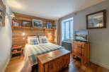 This cozy bedroom features a rustic wooden headboard and a charming wooden chest at the foot of the bed.
