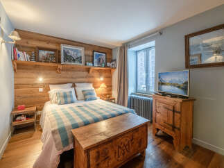 This cozy bedroom features a rustic wooden headboard and a charming wooden chest at the foot of the bed.
