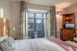 This charming bedroom offers a cozy retreat with its inviting ambiance and natural light.