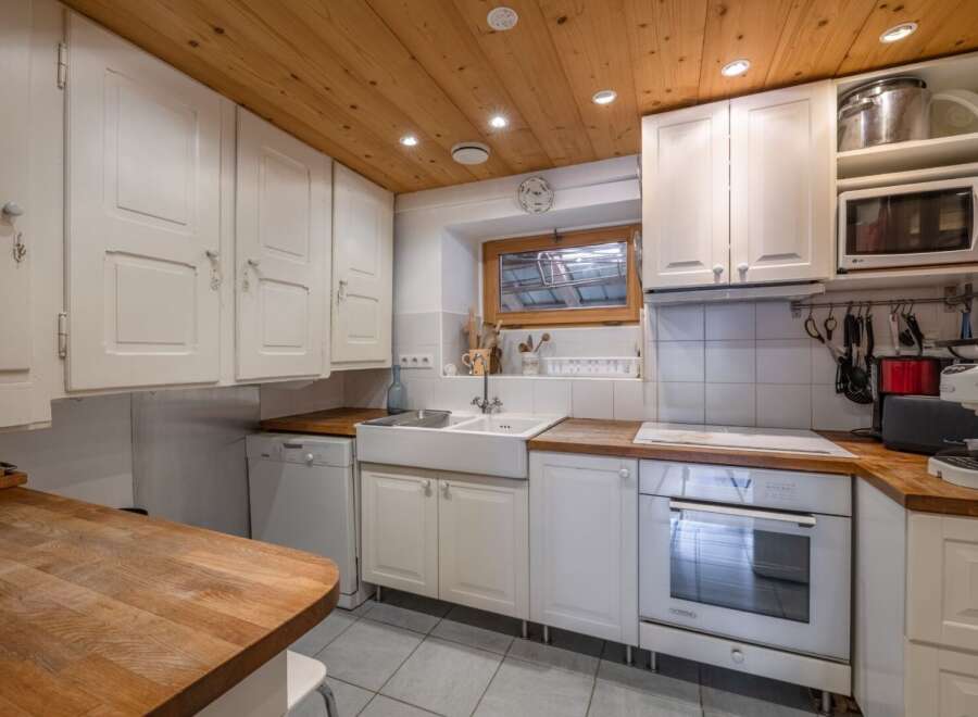 This charming kitchen boasts a warm, inviting atmosphere with its wooden ceiling and white cabinetry.