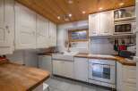 This charming kitchen boasts a warm, inviting atmosphere with its wooden ceiling and white cabinetry.