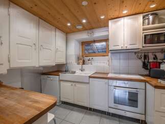 This charming kitchen boasts a warm, inviting atmosphere with its wooden ceiling and white cabinetry.