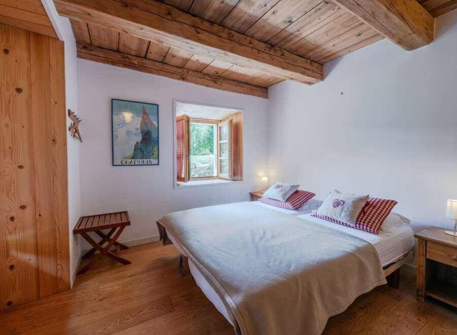 This charming bedroom features a cozy atmosphere with wooden beams and flooring, creating a warm and inviting space.