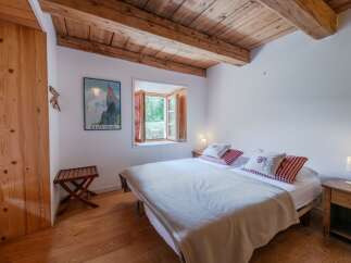 This charming bedroom features a cozy atmosphere with wooden beams and flooring, creating a warm and inviting space.
