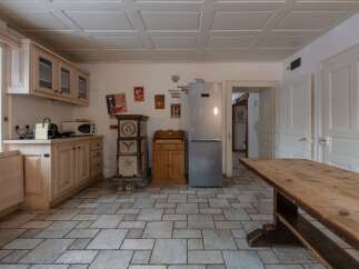 This charming kitchen features a rustic design with wooden cabinetry, a stone floor, and a large wooden table, creating a warm and inviting atmosphere.