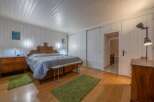This charming bedroom features a cozy atmosphere with wooden floors and white paneled walls.