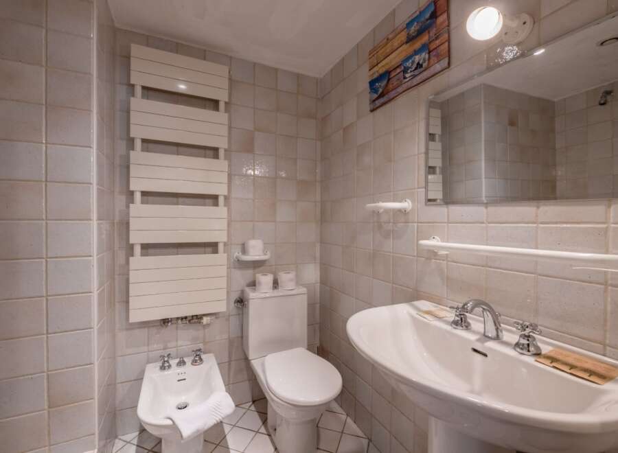 This charming bathroom features a classic design with tiled walls and a pedestal sink.