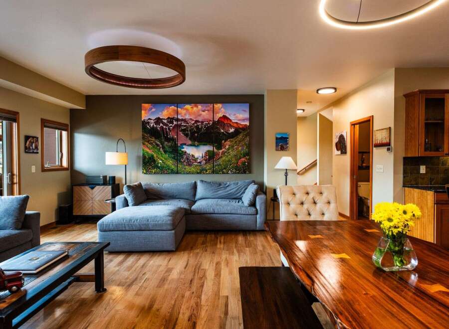 Experience luxury living in this stunning property, featuring a spacious living room with a modern sectional sofa and a captivating mountain landscape artwork.