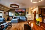 Experience luxury living in this stunning property, featuring a spacious living room with a modern sectional sofa and a captivating mountain landscape artwork.
