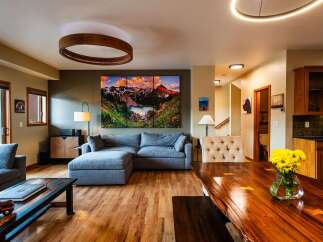 Experience luxury living in this stunning property, featuring a spacious living room with a modern sectional sofa and a captivating mountain landscape artwork.