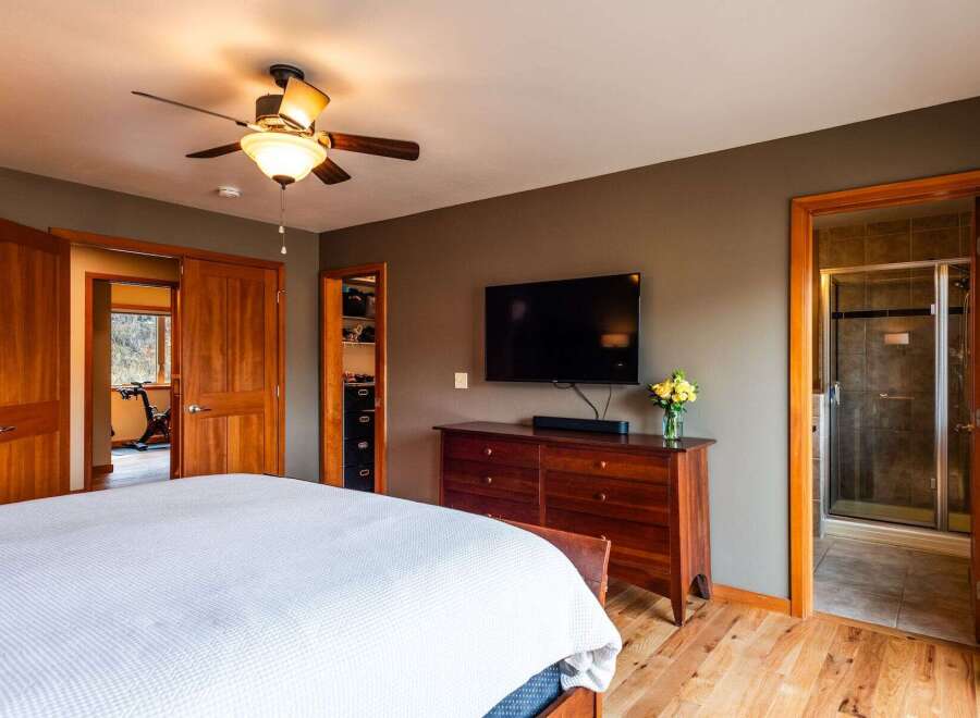 Step into this inviting bedroom, featuring a sleek flat-screen TV mounted above a stylish wooden dresser.