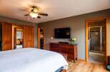 Step into this inviting bedroom, featuring a sleek flat-screen TV mounted above a stylish wooden dresser.