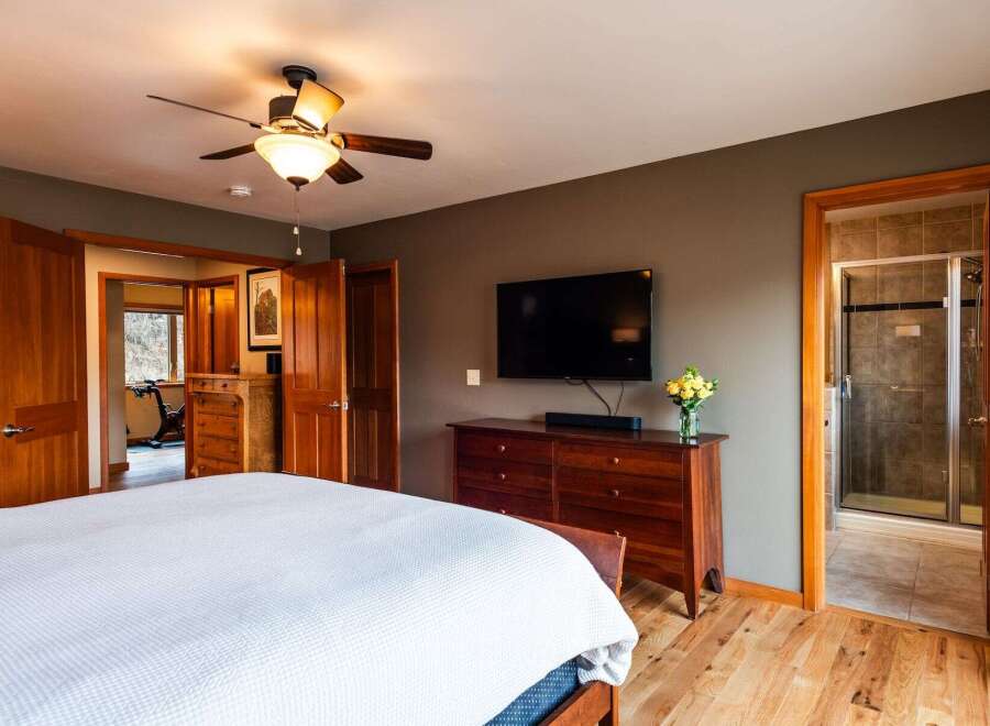 Step into this inviting bedroom, featuring a sleek flat-screen TV mounted above a stylish wooden dresser.