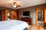 Step into this inviting bedroom, featuring a sleek flat-screen TV mounted above a stylish wooden dresser.