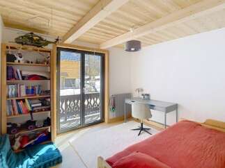 This charming bedroom features a cozy bed with a vibrant red cover, perfect for a relaxing retreat.