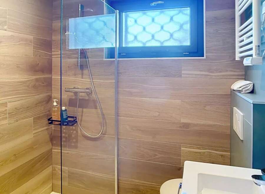 Step into a modern bathroom oasis! This stunning space features a sleek glass shower, complemented by elegant wood-look tile.