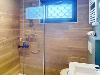 Step into a modern bathroom oasis! This stunning space features a sleek glass shower, complemented by elegant wood-look tile.