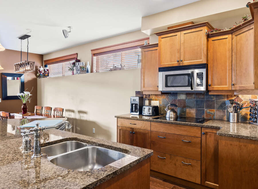 This stunning kitchen boasts beautiful granite countertops and rich wooden cabinetry, creating a warm and inviting atmosphere.