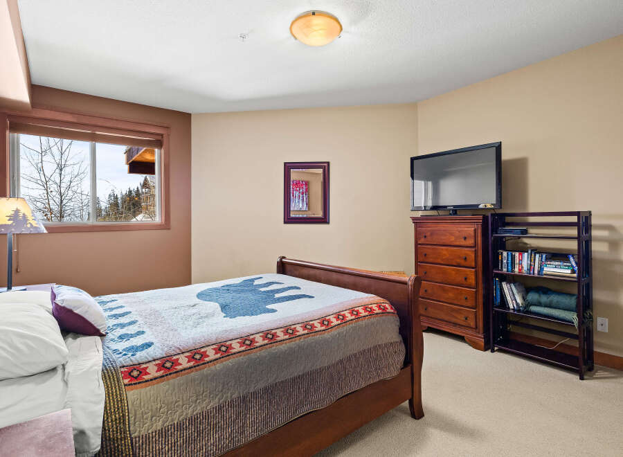 This cozy bedroom features a comfortable bed with a unique quilt and a charming lamp.
