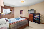 This cozy bedroom features a comfortable bed with a unique quilt and a charming lamp.