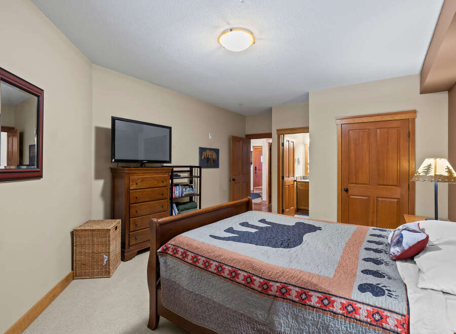 This cozy bedroom features a comfortable bed with a unique bear-themed quilt, perfect for a relaxing retreat.