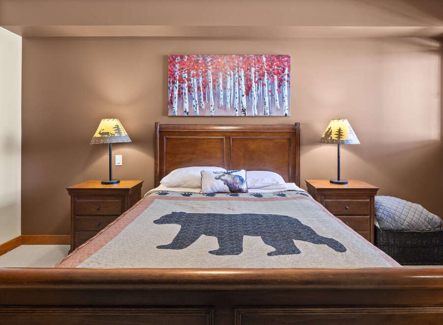This cozy bedroom features a rustic design with a bear-themed quilt and matching lampshades.