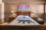 This cozy bedroom features a rustic design with a bear-themed quilt and matching lampshades.