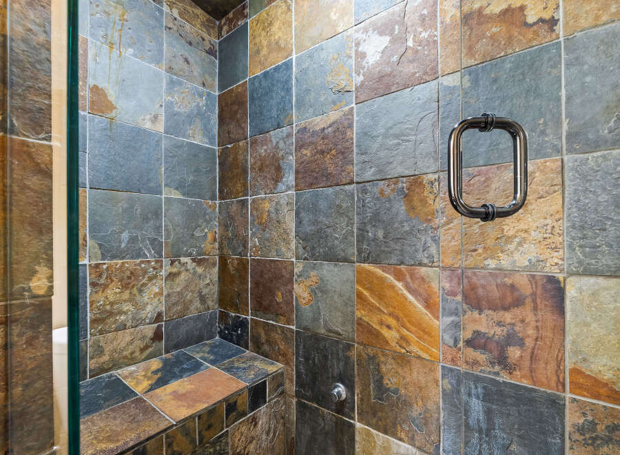 Step into luxury with this stunning shower featuring exquisite stone tile work.