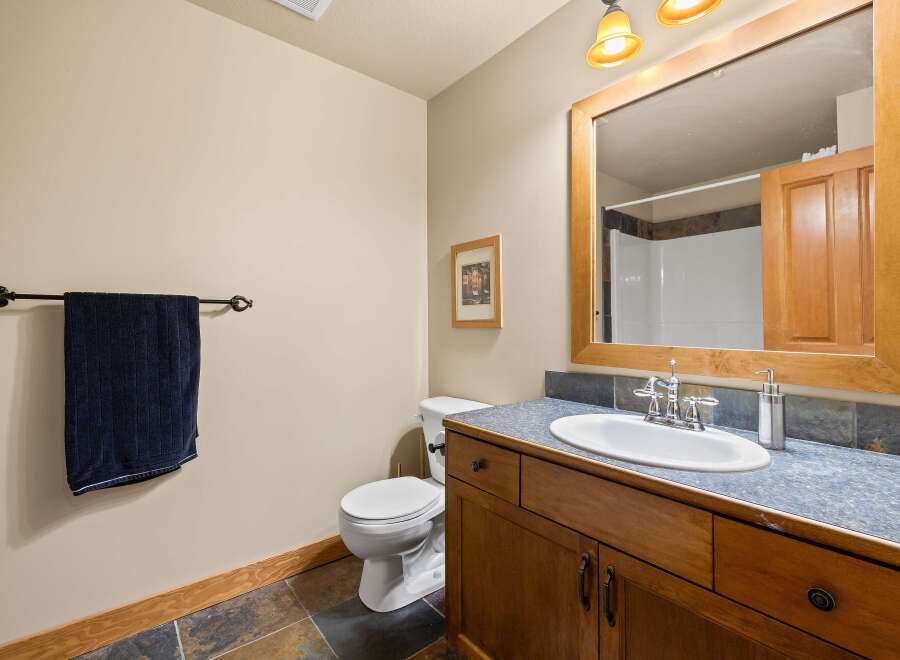 This charming bathroom features a warm, inviting ambiance with its wooden vanity and framed mirror.