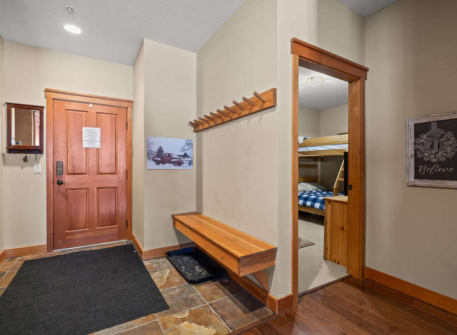 Step into this inviting entryway, featuring a warm wooden door and a convenient bench.