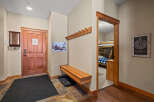 Step into this inviting entryway, featuring a warm wooden door and a convenient bench.