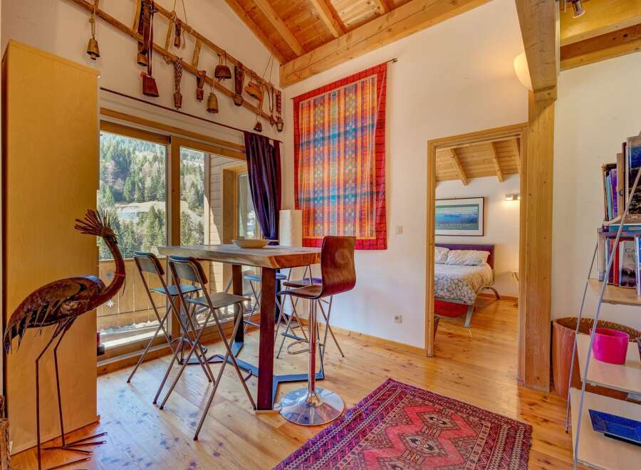 This charming property boasts a cozy dining area with a rustic wooden table and stylish bar stools, perfect for enjoying meals.