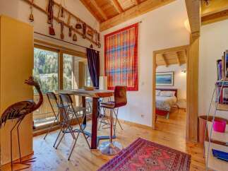 This charming property boasts a cozy dining area with a rustic wooden table and stylish bar stools, perfect for enjoying meals.
