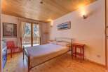 This charming bedroom features a cozy wooden ceiling and flooring, creating a warm and inviting atmosphere.