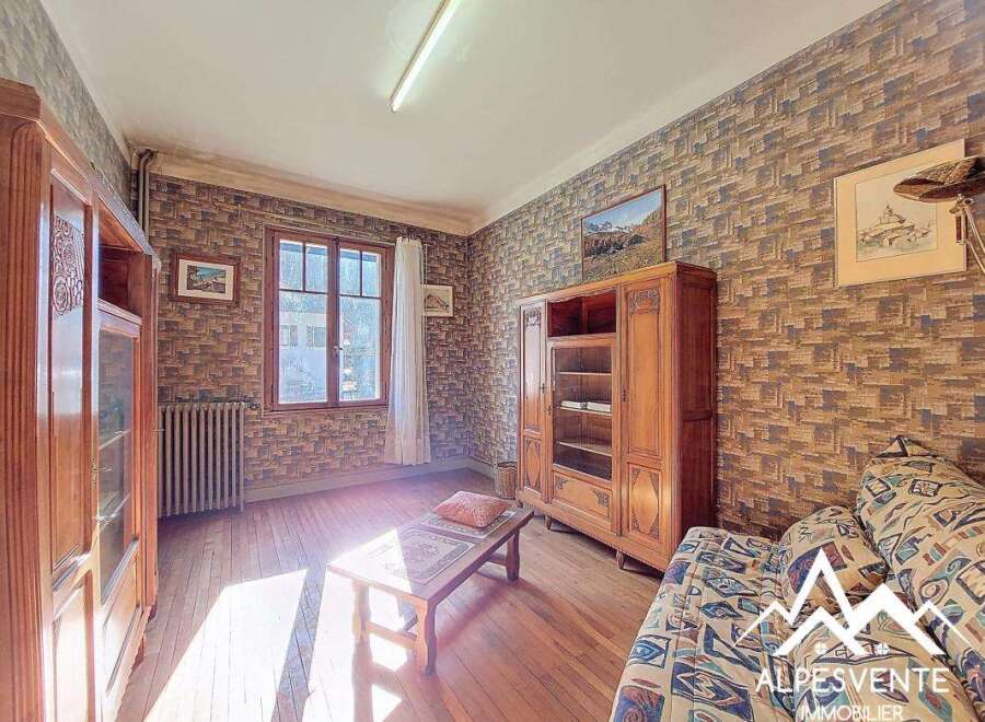 Discover the charm of this property, featuring a cozy living space with wooden floors and a unique brick-style wallpaper.