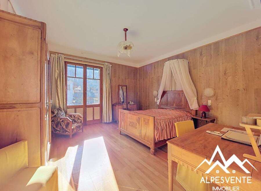 Discover the charm of this inviting bedroom, featuring a classic wooden bed and elegant wooden paneling.