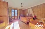 Discover the charm of this inviting bedroom, featuring a classic wooden bed and elegant wooden paneling.