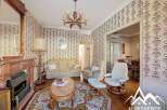 Step into this charming property, featuring a cozy living room with a fireplace and elegant chandelier.