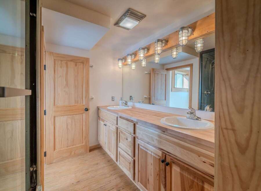 This stunning bathroom features a custom wooden vanity with dual sinks, offering ample storage and a touch of rustic elegance.