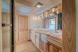 This stunning bathroom features a custom wooden vanity with dual sinks, offering ample storage and a touch of rustic elegance.