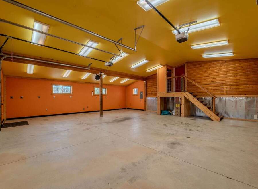 This spacious garage offers ample room for vehicles and storage, featuring a vibrant orange interior and a bright yellow ceiling.