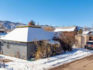 Nestled in a serene winter landscape, this charming property boasts a snow-covered roof and a cozy ambiance.