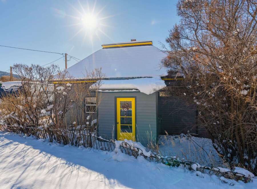 This charming property features a cozy cabin with a vibrant yellow door, perfect for a winter retreat.
