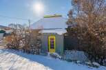 This charming property features a cozy cabin with a vibrant yellow door, perfect for a winter retreat.