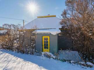 This charming property features a cozy cabin with a vibrant yellow door, perfect for a winter retreat.