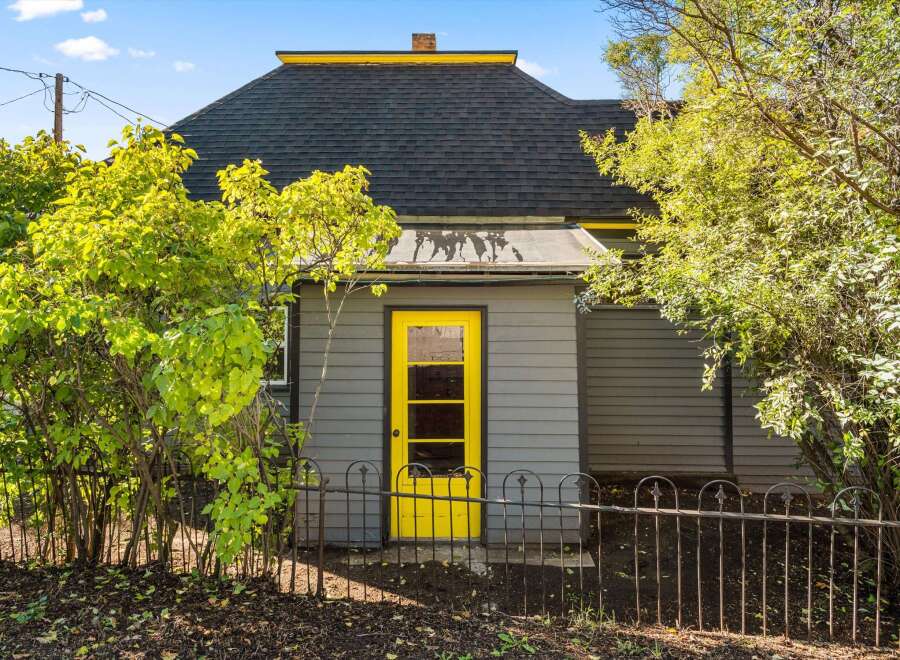 Charming home with a vibrant yellow door and a welcoming wrought iron fence.