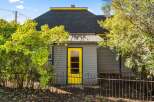 Charming home with a vibrant yellow door and a welcoming wrought iron fence.