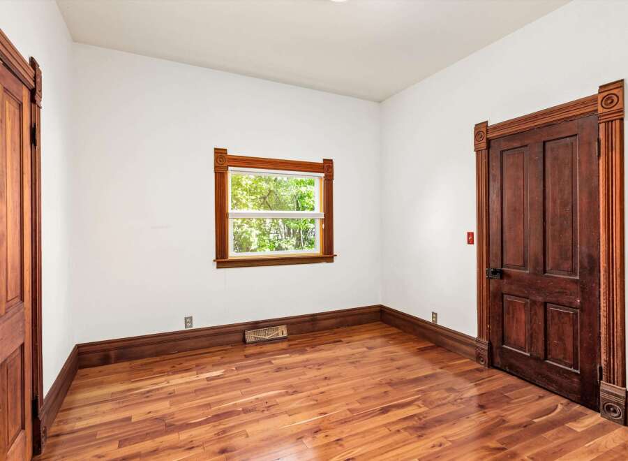 Step into this charming room, featuring stunning hardwood floors and elegant wooden door frames.