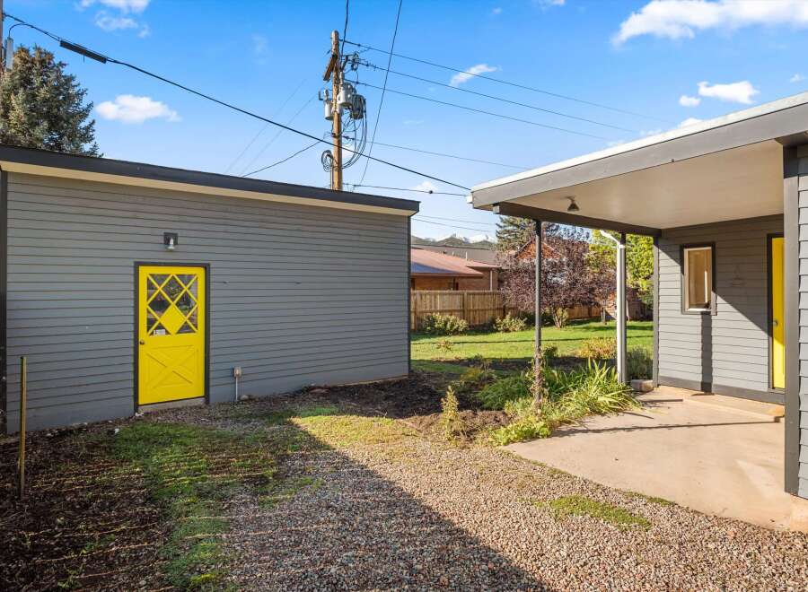 This charming property boasts a striking exterior with a vibrant yellow door, adding a pop of color to the gray siding.